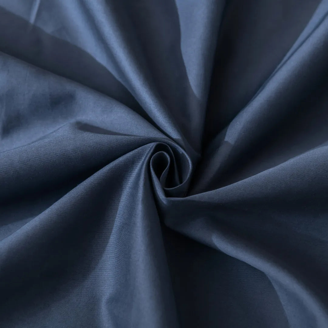A close-up view of a swirl in a navy blue fabric with a smooth, luxurious texture ideal for Linenly's Luxe Sateen Pillowcase Set - Midnight featuring an envelope closure design.
