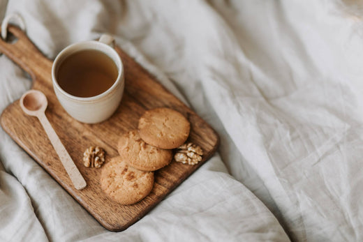 a board with a cup of tea and cookies in bed