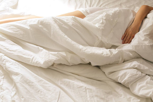 a person lying in bed embracing a white bamboo bed sheet cover