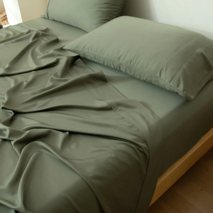 A neatly made bed with soft, environmentally friendly Linenly Bamboo Sheet Set in olive green, inviting a peaceful and comfortable rest.