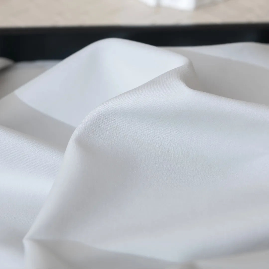 A close-up of Linenly’s Luxe Cotton Sateen Flat Sheet in Silver, showcasing smooth, soft folds and a silky texture with a blurred background that highlights the premium cotton surface.