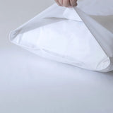 A hand is placing a pillow into the Linenly Luxe Cotton Sateen Pillowcase Set in white, shown against a plain white background.
