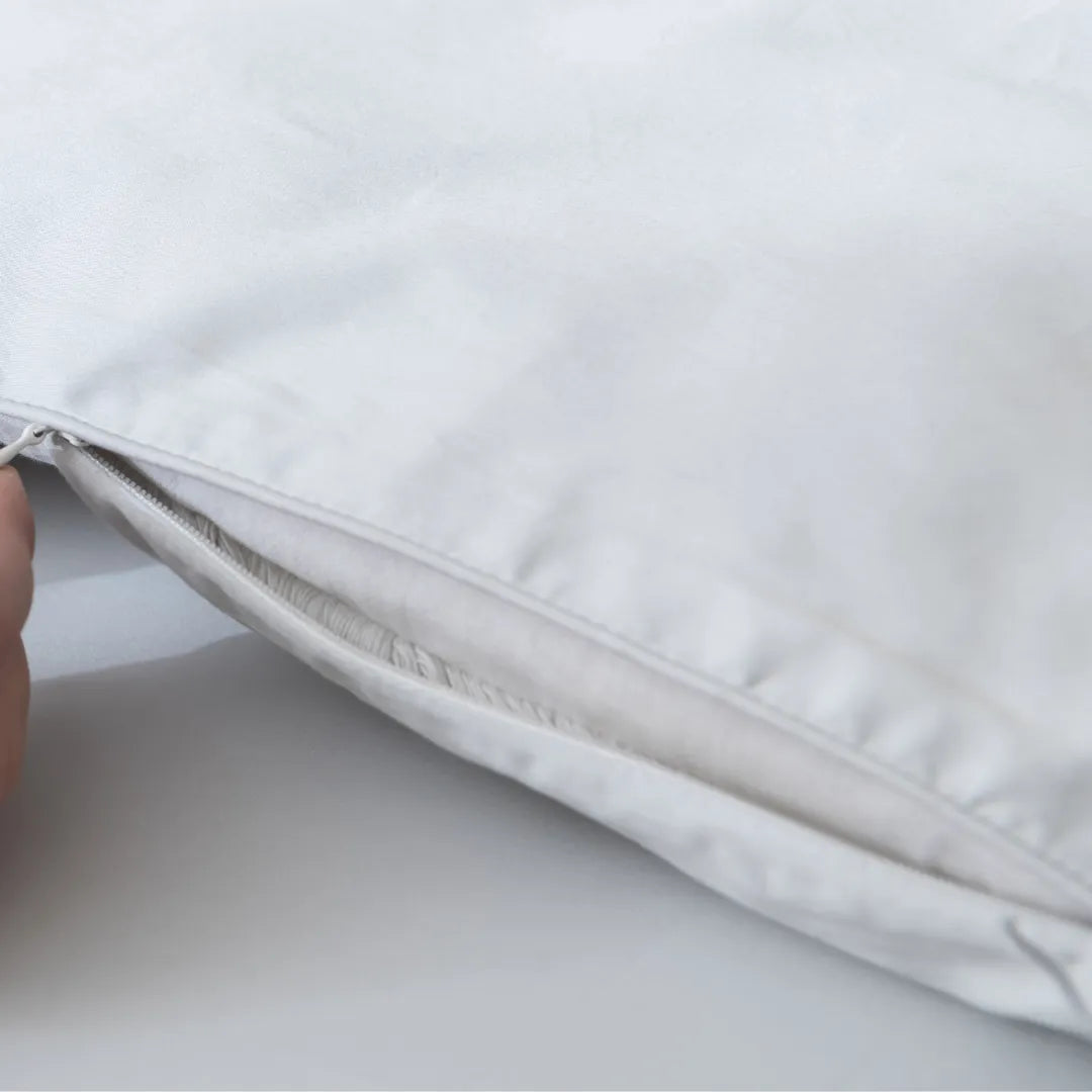 A close-up of the Linenly Luxe Cotton Sateen Quilt Cover in Silver shows its soft, long staple cotton texture as a hand holds the edge near a partially opened zipper, revealing the inner insert.