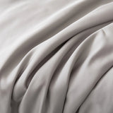 Close-up of smooth, light gray fabric with soft folds—just like the elegant texture of our Linenly Bamboo Sheet Set - Silver. Experience true luxury with these silky bamboo sheets from Linenly.